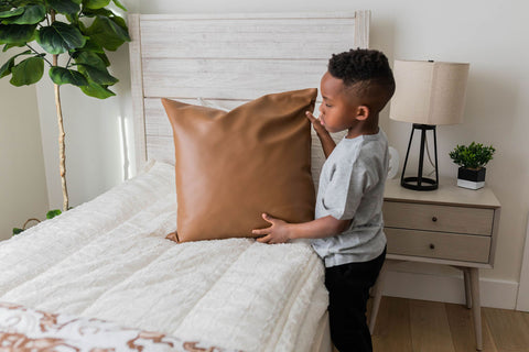A young boy makes his bed with Beddy's zipper bedding.