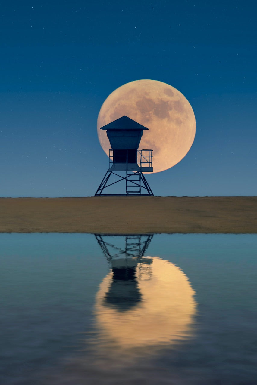 Full moon at the beach behind a lifeguard tower