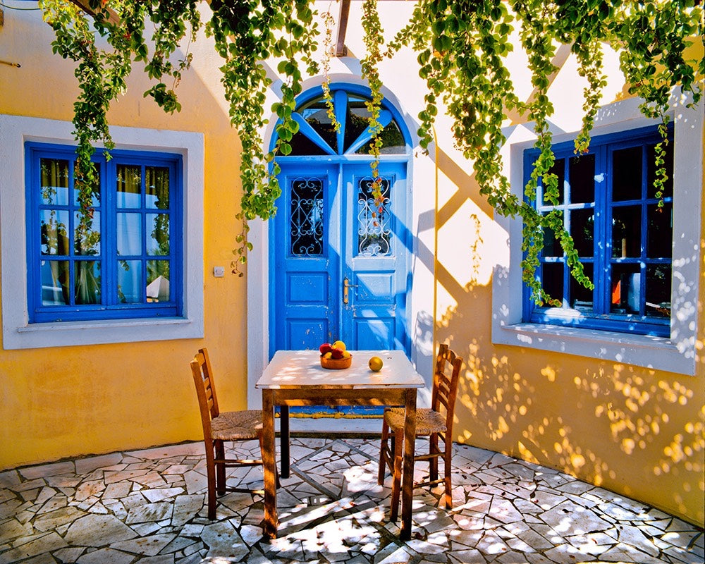 Sunny Greek courtyard with blue doors and windows