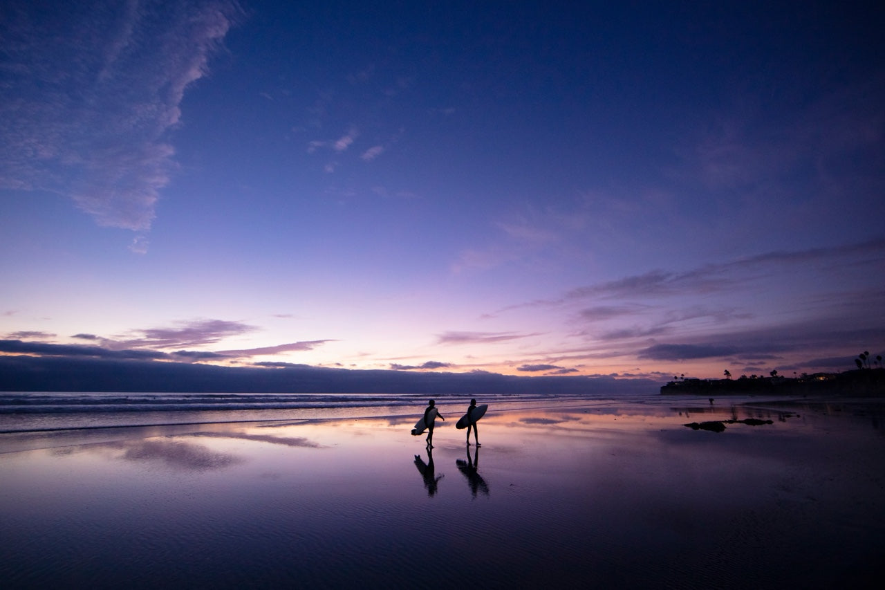 Surfers on the beach at twilight