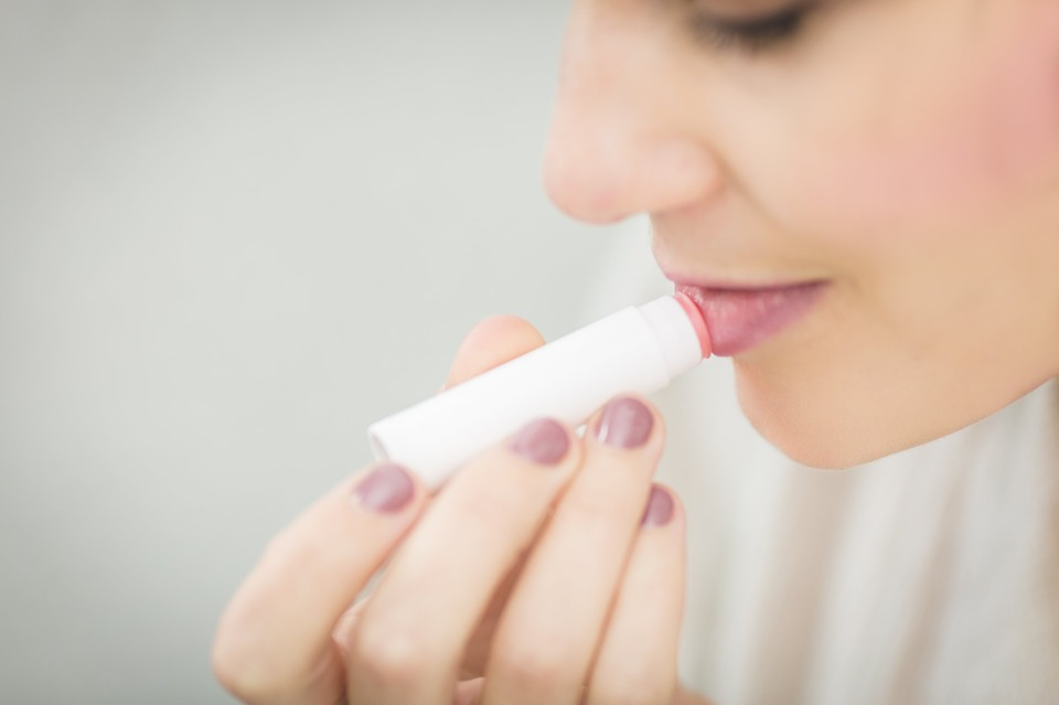 A young woman applying chapstick to her lips