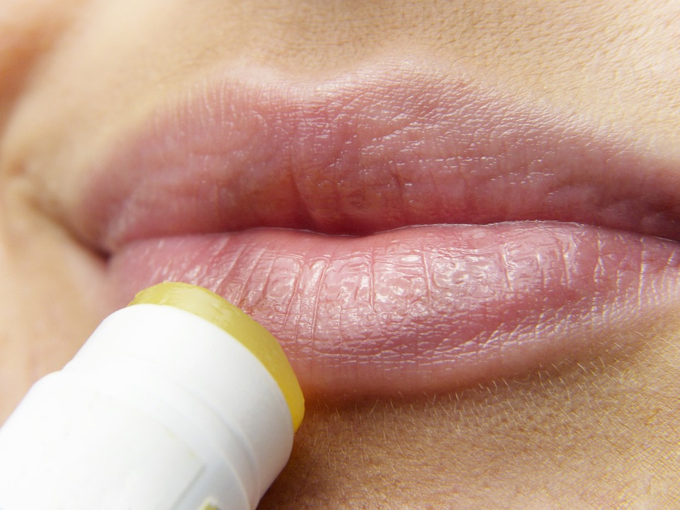 Close up of a woman with pink lips applying chapstick