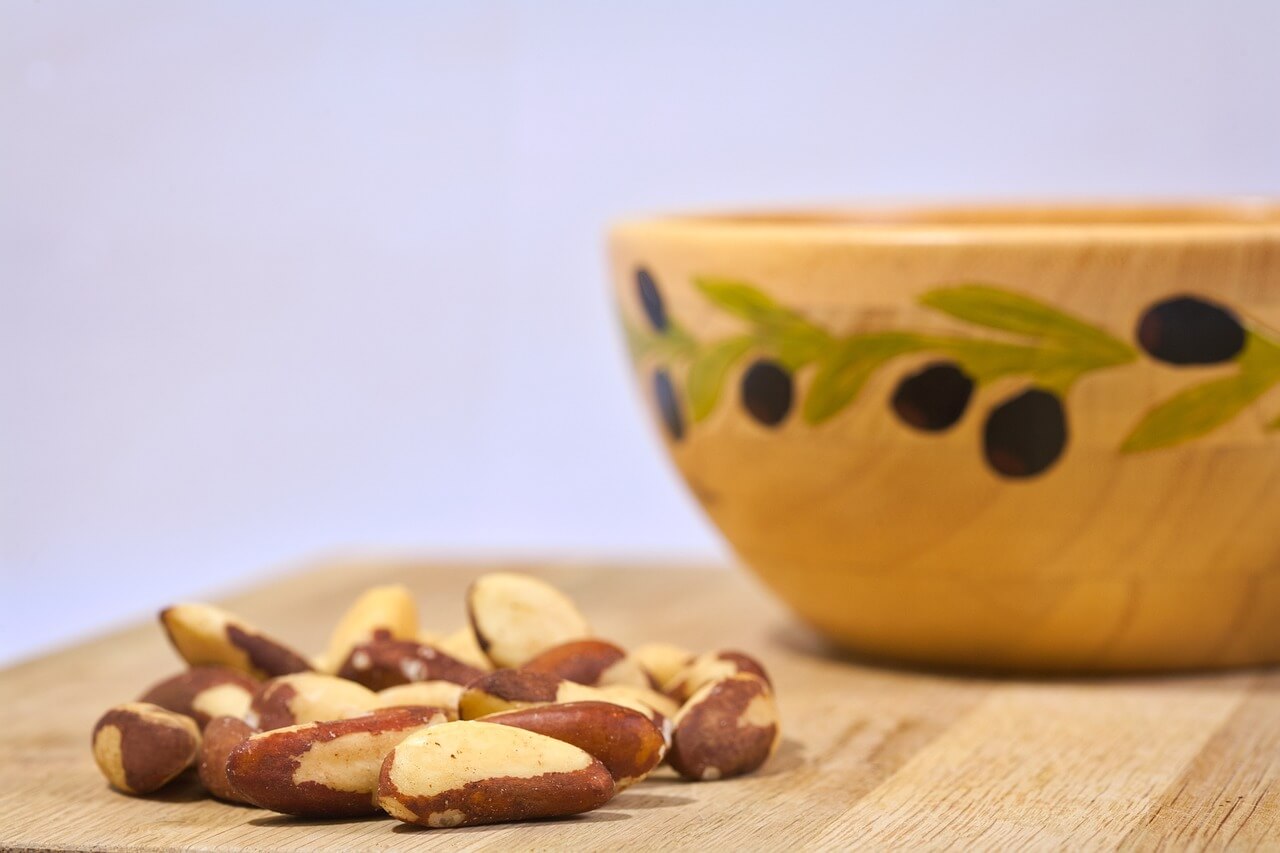 Brazil nuts on a wooden surface next to a bowl
