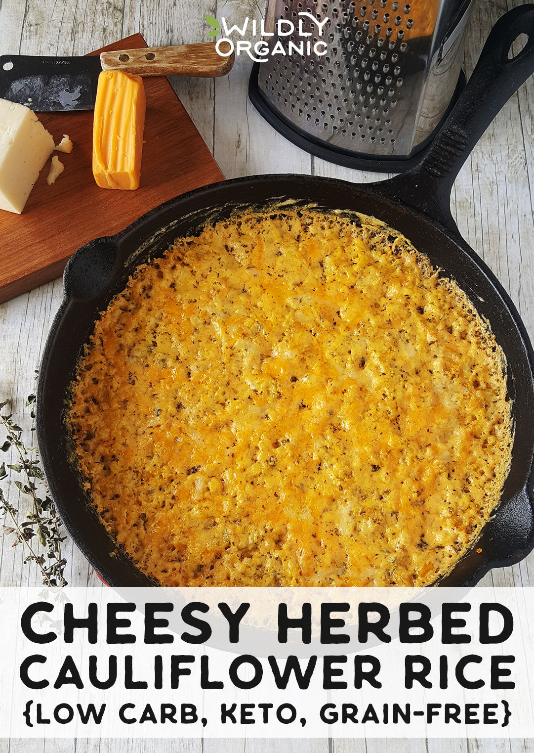 Photo of Cheesy Herbed Cauliflower Rice in a cast iron skillet with cheese, a cutting board, knife, and grater in the background.