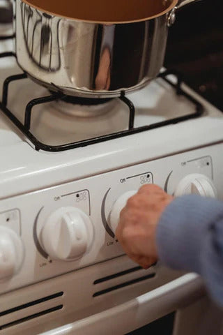 Hand turning on a stove to warm the oil