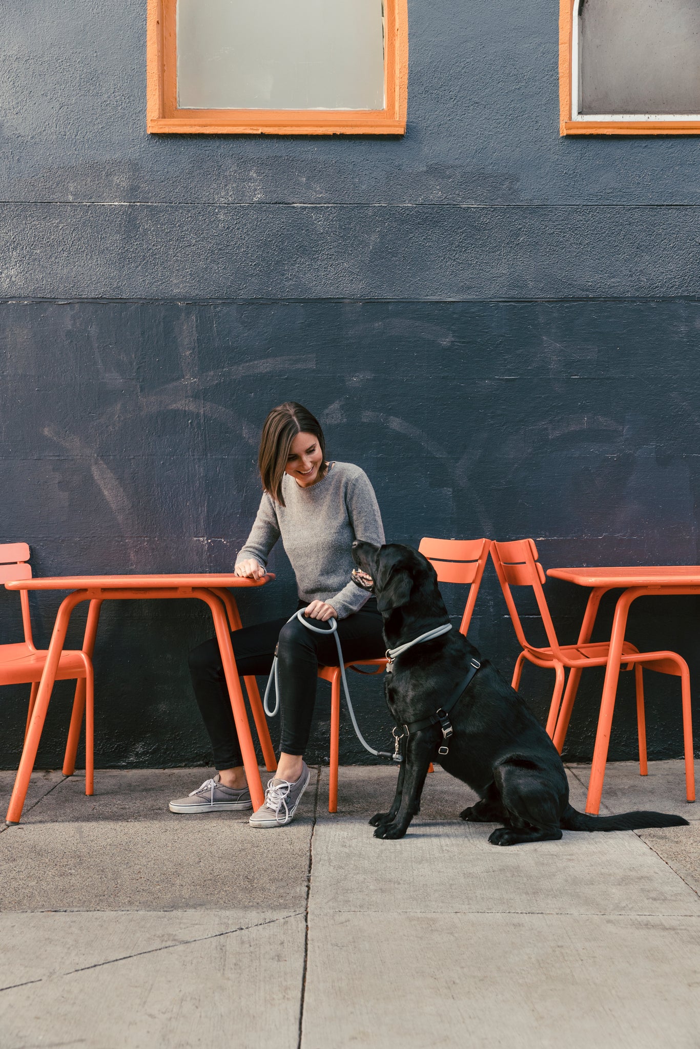 Woman sits outside on city street with dog - Atlas Pet Company Top Five Towns for Dog Lovers