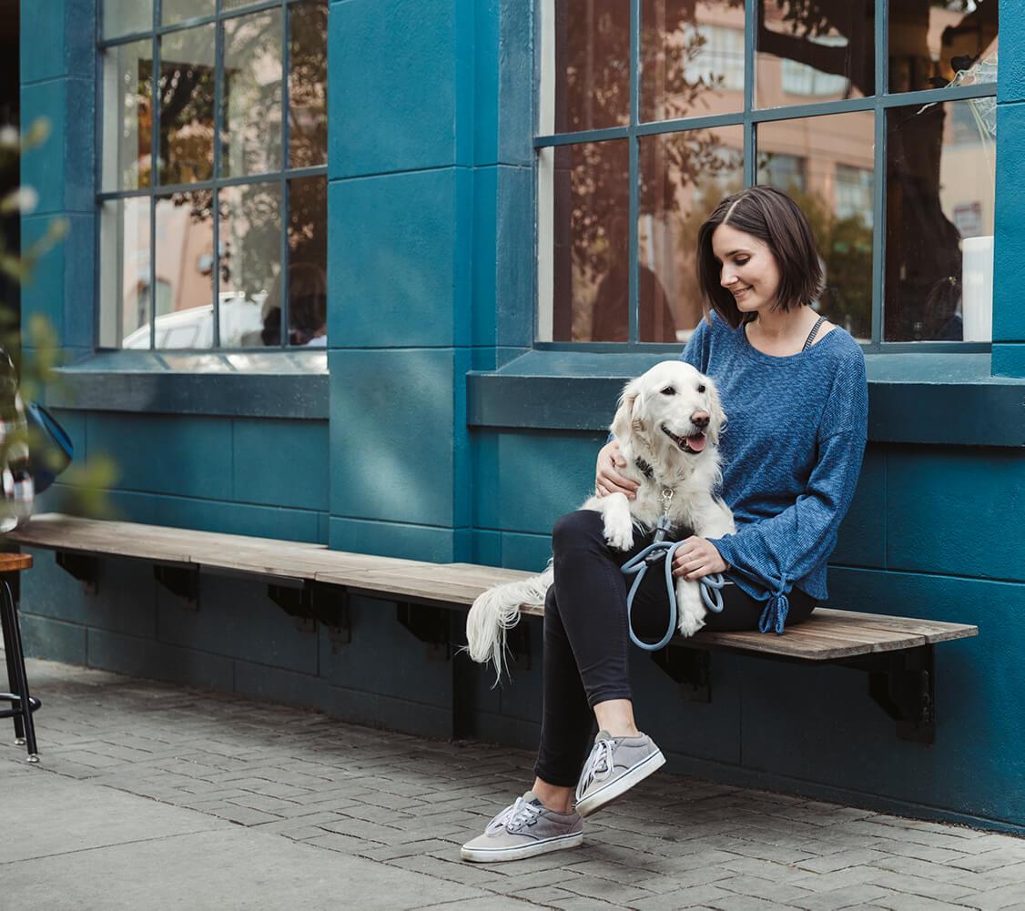 Dog sits on woman's lap outside on a city street- Atlas Pet Company Top Five Towns for Dog Lovers