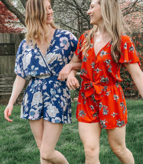 two girls linked arms wearing floral rompers