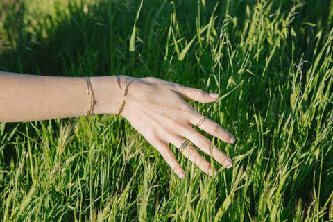 Model wear Jennie Kwon rings and brushes hand through grass