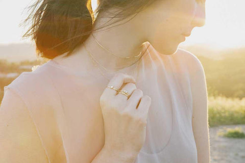 Model wearing Jennie Kwon rings standing in a field at sunset