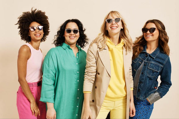 Four smiling young women wearing bright colors and polarized sunglasses.