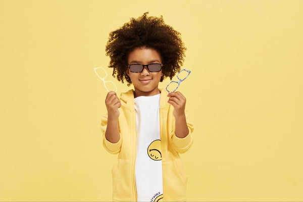 Kids sunglasses: kid holding 2 pairs of eyeglasses