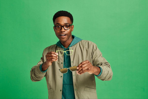 Single vision lenses vs progressive: man holding 2 pairs of eyeglasses