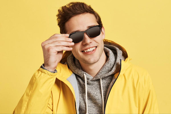 Man wearing a pair of sunglasses while smiling at the camera