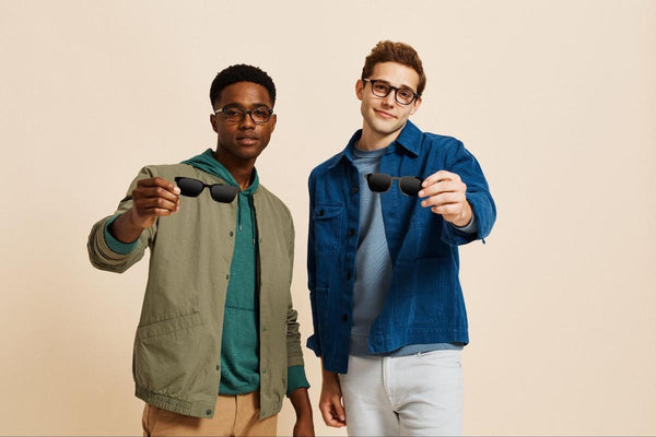 Men holding 2 pairs of eyeglasses