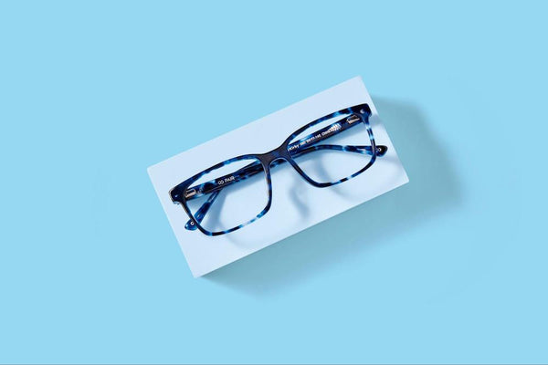 Best glasses for oval faces: Blue rectangular tortoise eyeglasses on a blue background.