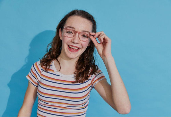 A smiling girl touching the side of her Twain glasses from Pair Eyewear.