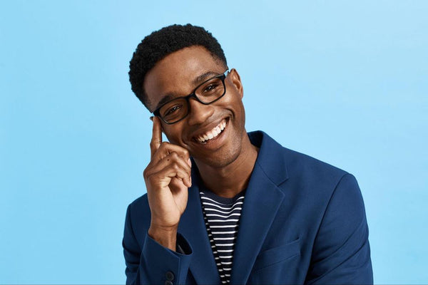 A man smiling while wearing Pair Eyewear Finley glasses in front of a blue background.