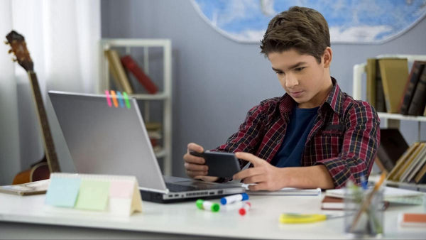 Blue light glasses for kids: teenage boy using a phone