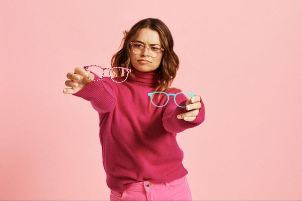Woman holding 2 pairs of eyeglasses