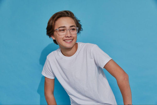 A young boy wearing a white T-shirt and kids prescription glasses.