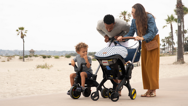 Parents and Two Children Going for a Walk on the Beach using an Infant Stroller