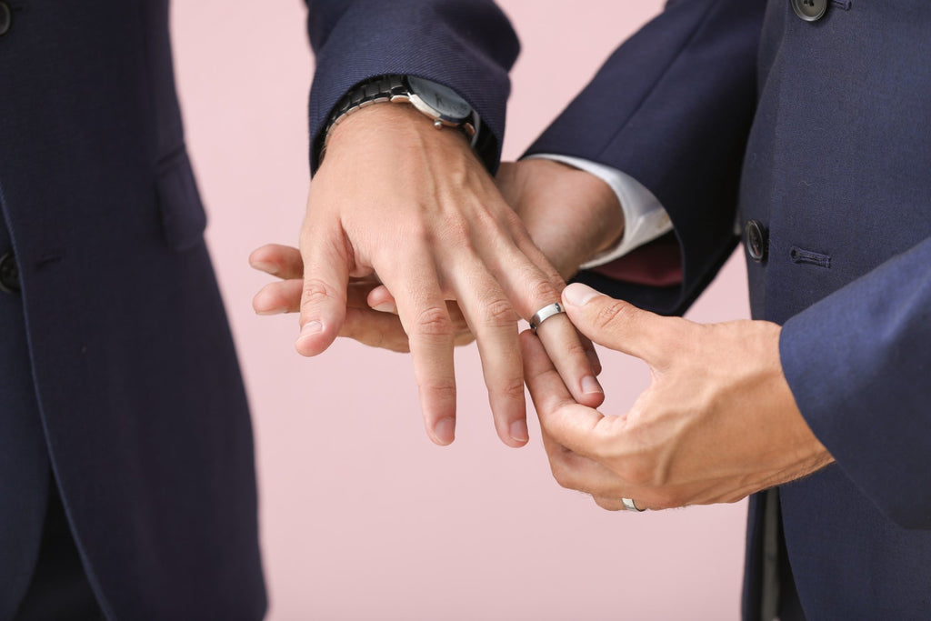 Grooms exchanging wedding bands with one another