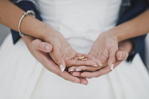 Married couple holding his and hers wedding bands