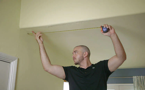 A technician determining the exact length of track needed for room divider installation