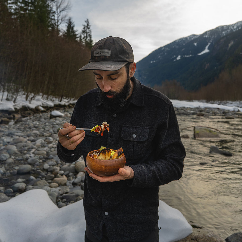Man eating bowl of chili in mountains at camp