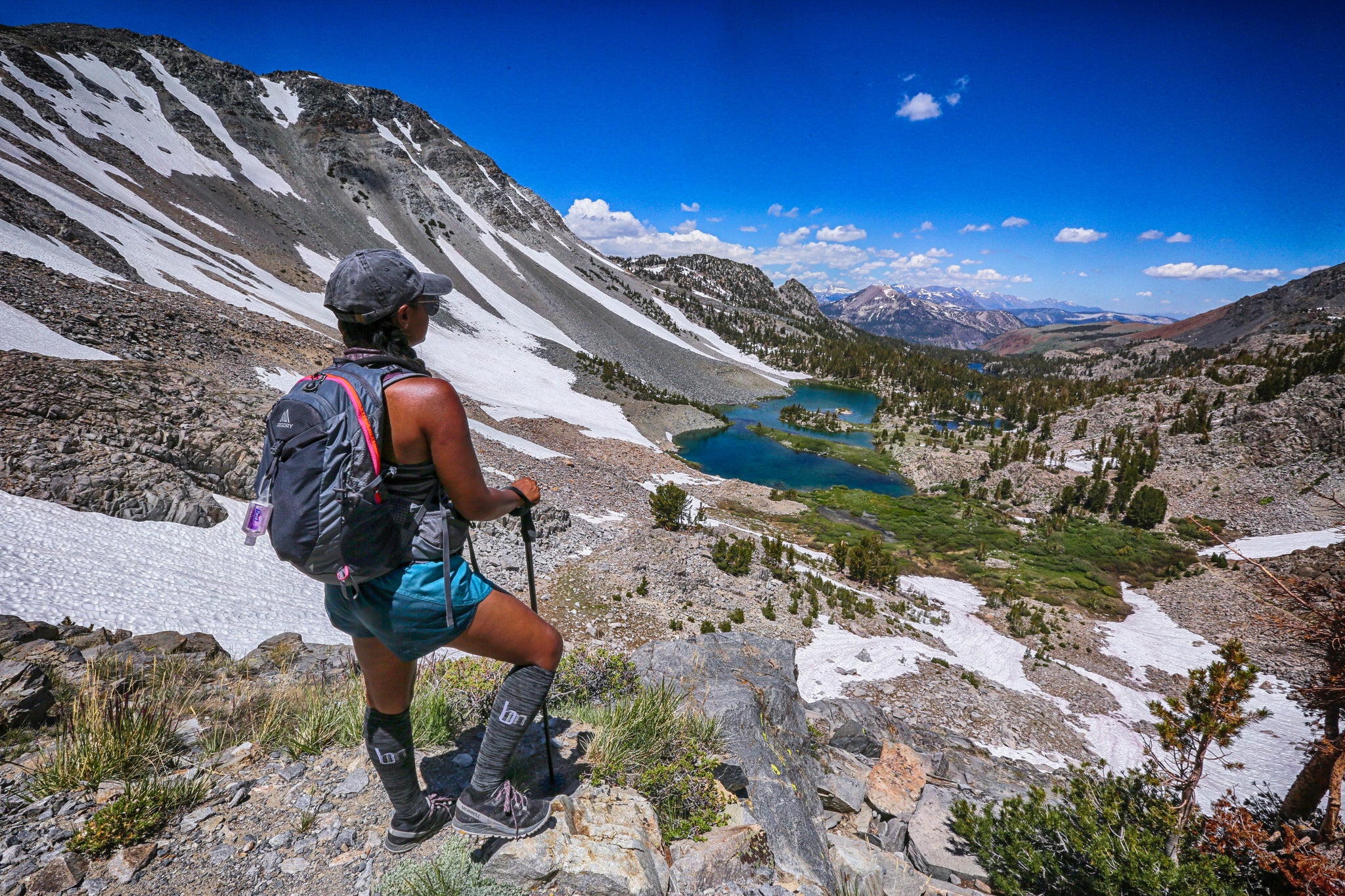 Backpacker looks over a mountain lake trail