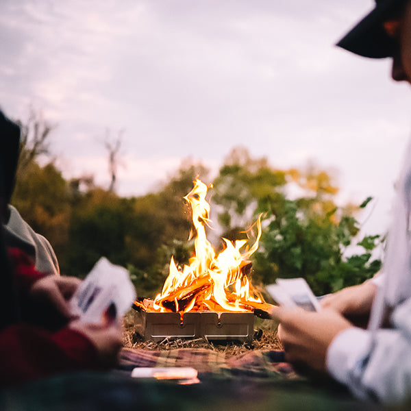 Friends playing cards beside outdoor fire pit