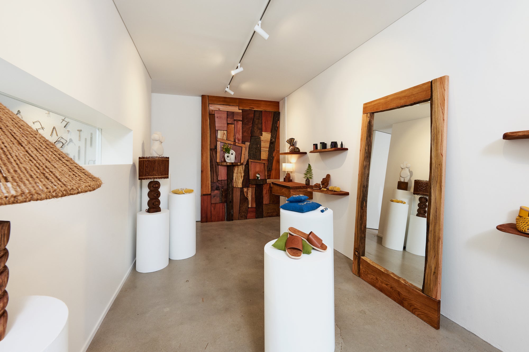 Wide angle image of Holly's shop including wooden wall, wooden framed mirror and white jewellery plinths