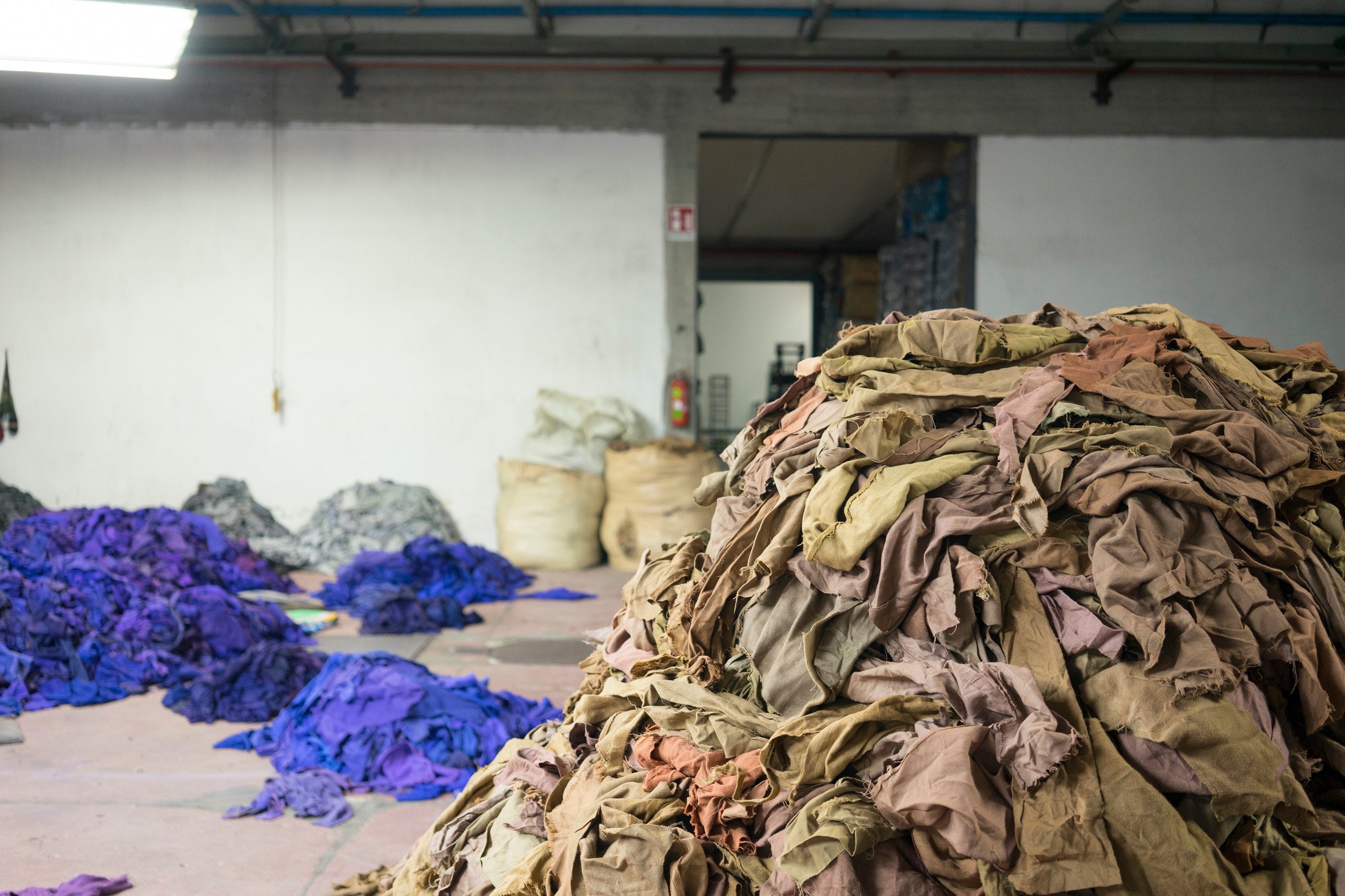 Used woollen garments shredded and sorted into colour piles, ready for recycling