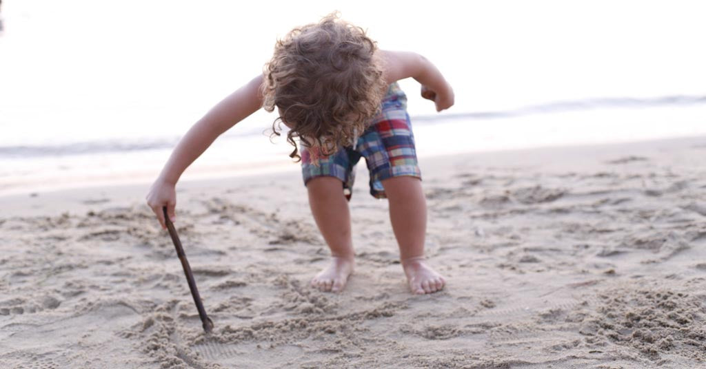 Boy making marks in sand