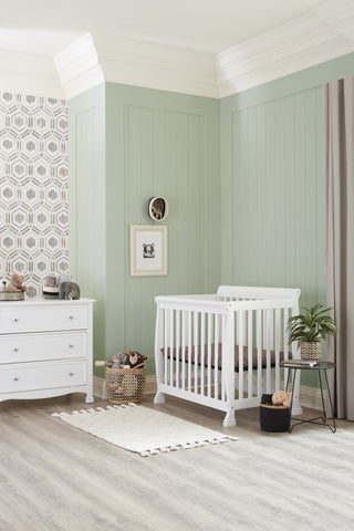 DaVinci Kalani Mini Crib in White with matching 3-Drawer Dresser in a cool sage room with monochrome accent wallpaper