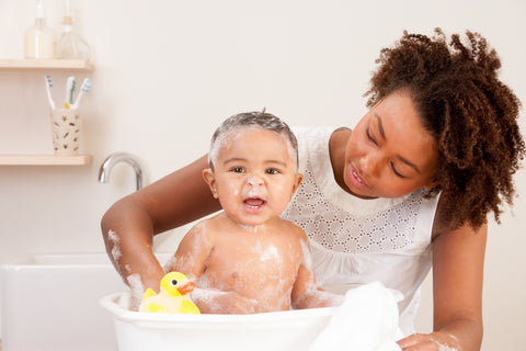 Mom giving her baby a bath in small tub for infants