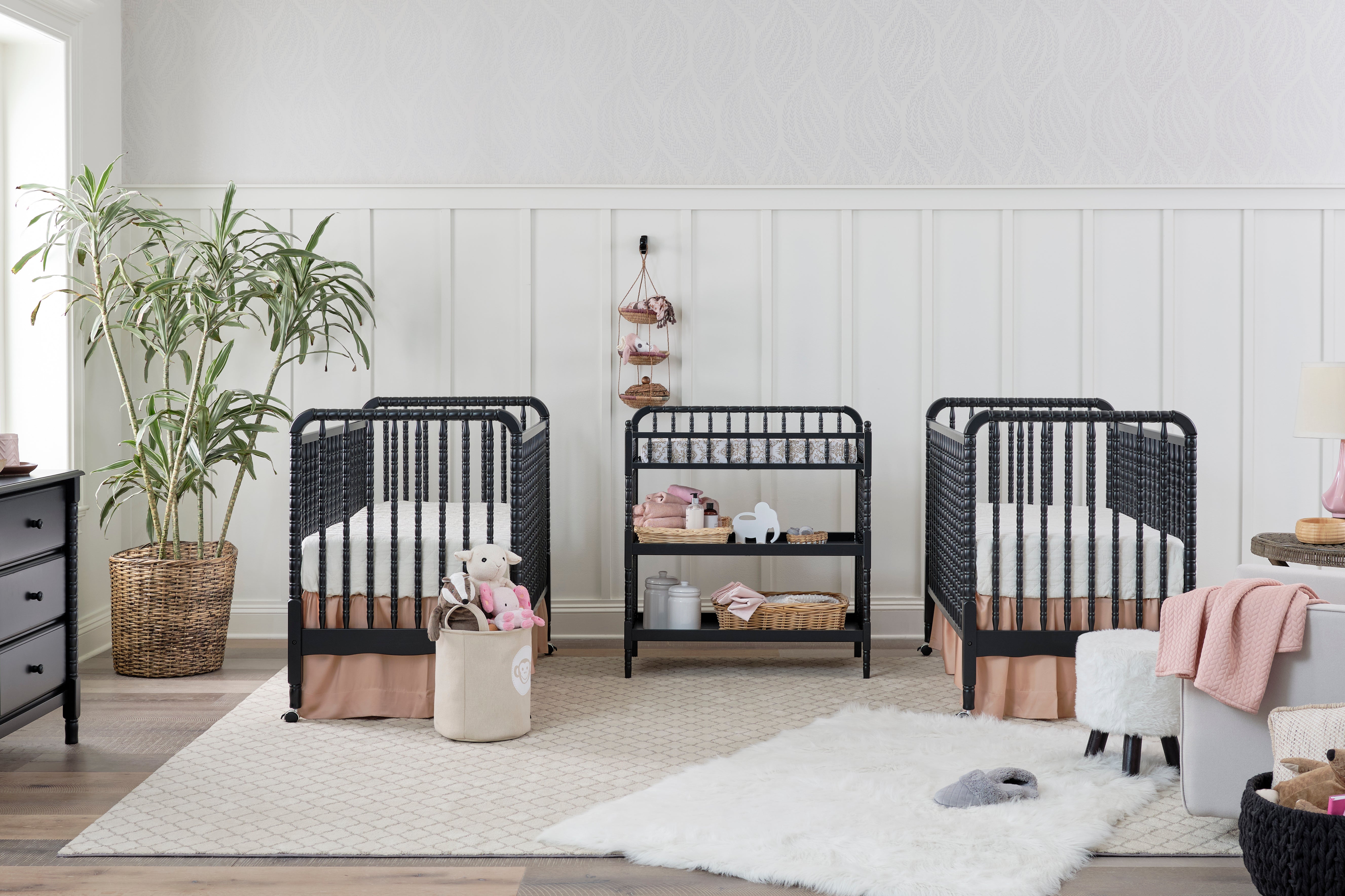 Twin Nursery featuring DaVinci Jenny Lind Cribs, Changing Table, and 6-Drawer Dresser in Ebony Finish set against elegant wainscoting 