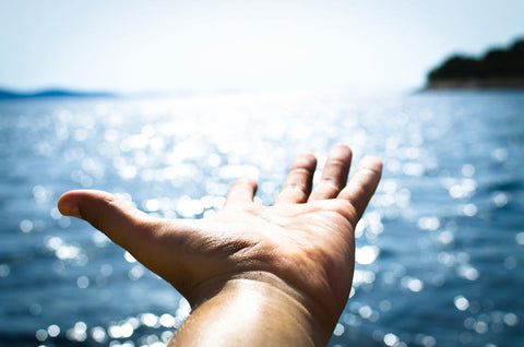 hand reaching out to ocean