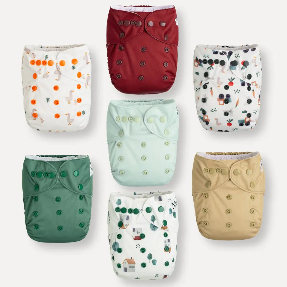 Variety of colorful cloth diapers with different patterns and snap buttons.