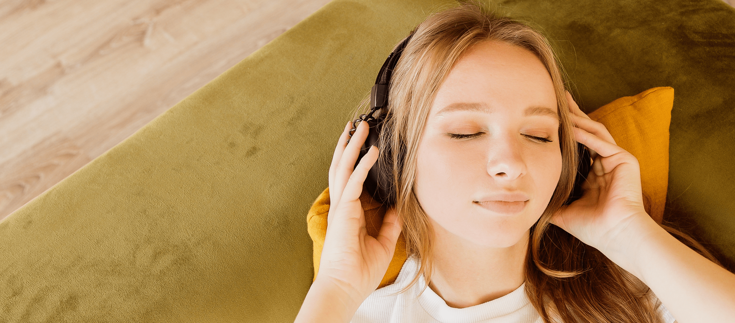 A woman is listening to music while laying on a couch.