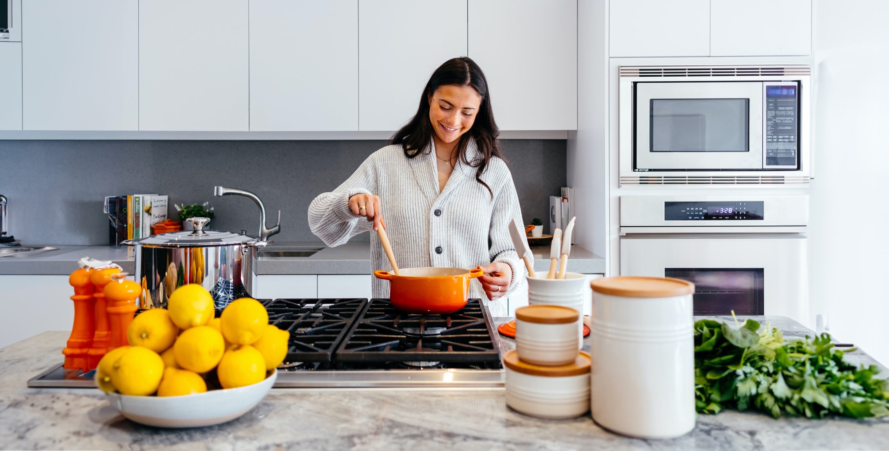 A woman is smiling as she cooks in the kitchen.