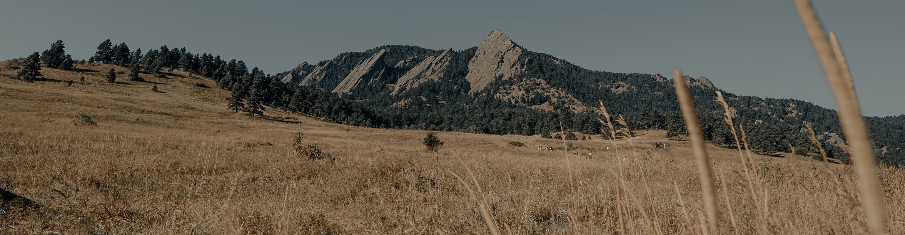 Scenic view of the majestic Boulder Mountains, with towering peaks, lush green valleys, and a brilliant blue sky on a sunny day.