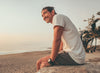 Man sitting down smiling on the beach.