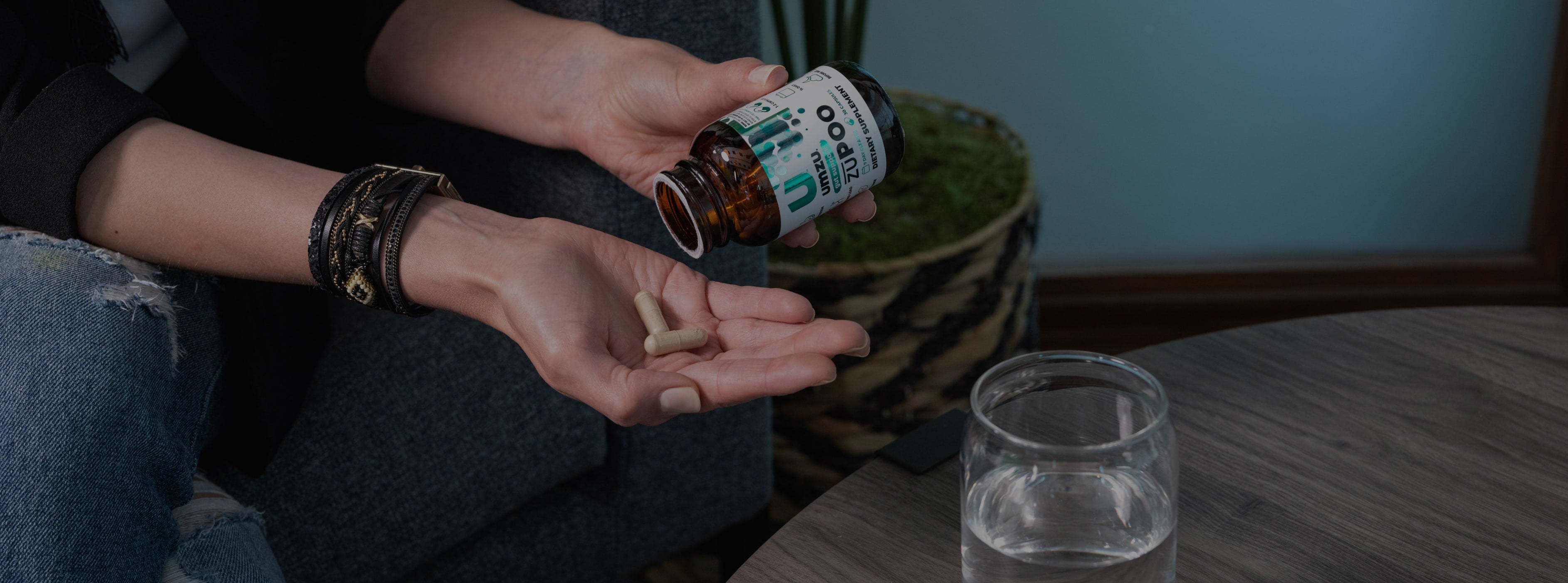 A woman holding a bottle of zuPoo with 2 capsules in her hand.