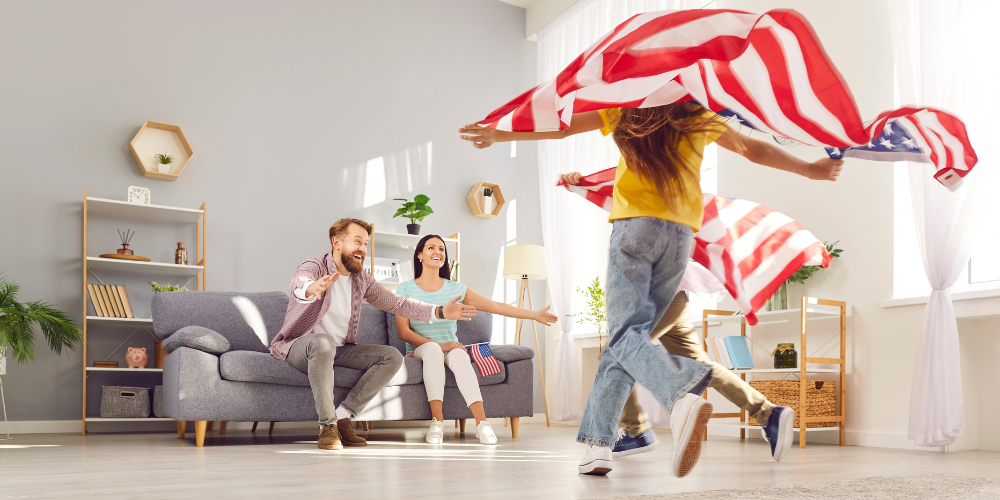 Family in living room, two children running toward their parents holding the American flag