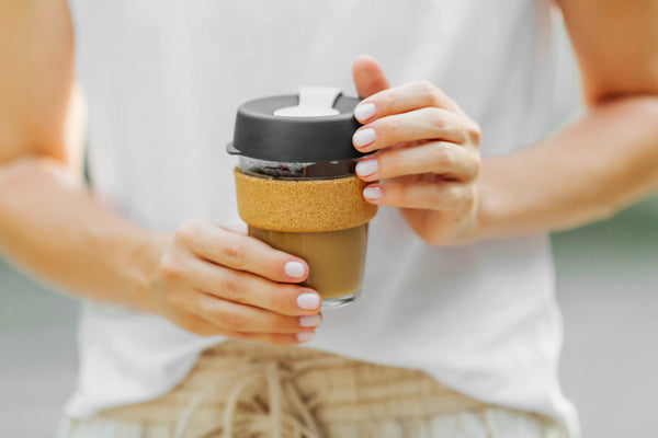 Woman holding reusable coffee cup full of black coffee.