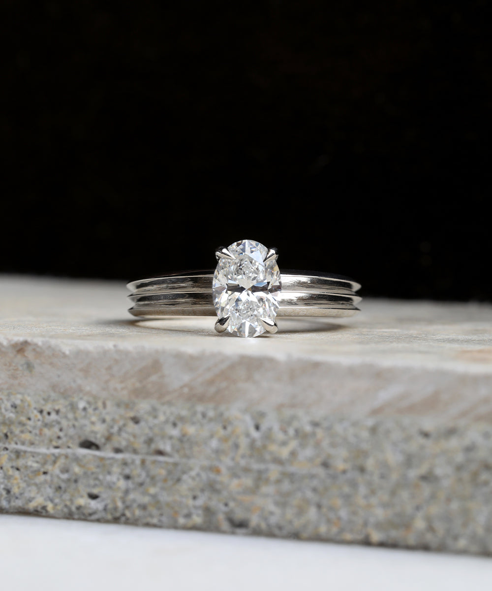 Clean and minimal oval cut diamond engagement ring with a sleek platinum double knife edge band.