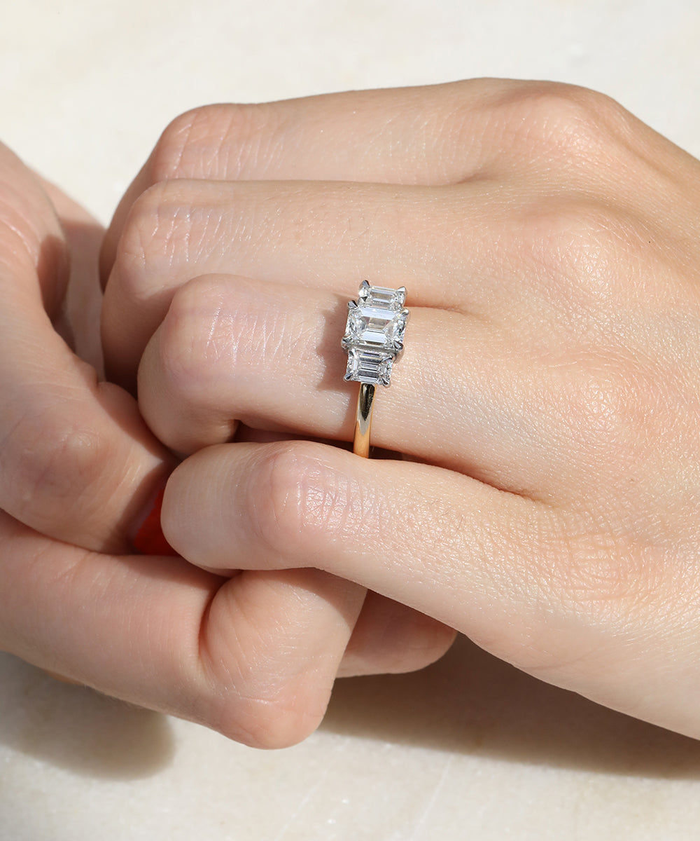Bespoke Emerald cut diamond trilogy engagement ring with a split platinum setting and 18ct yellow gold band.