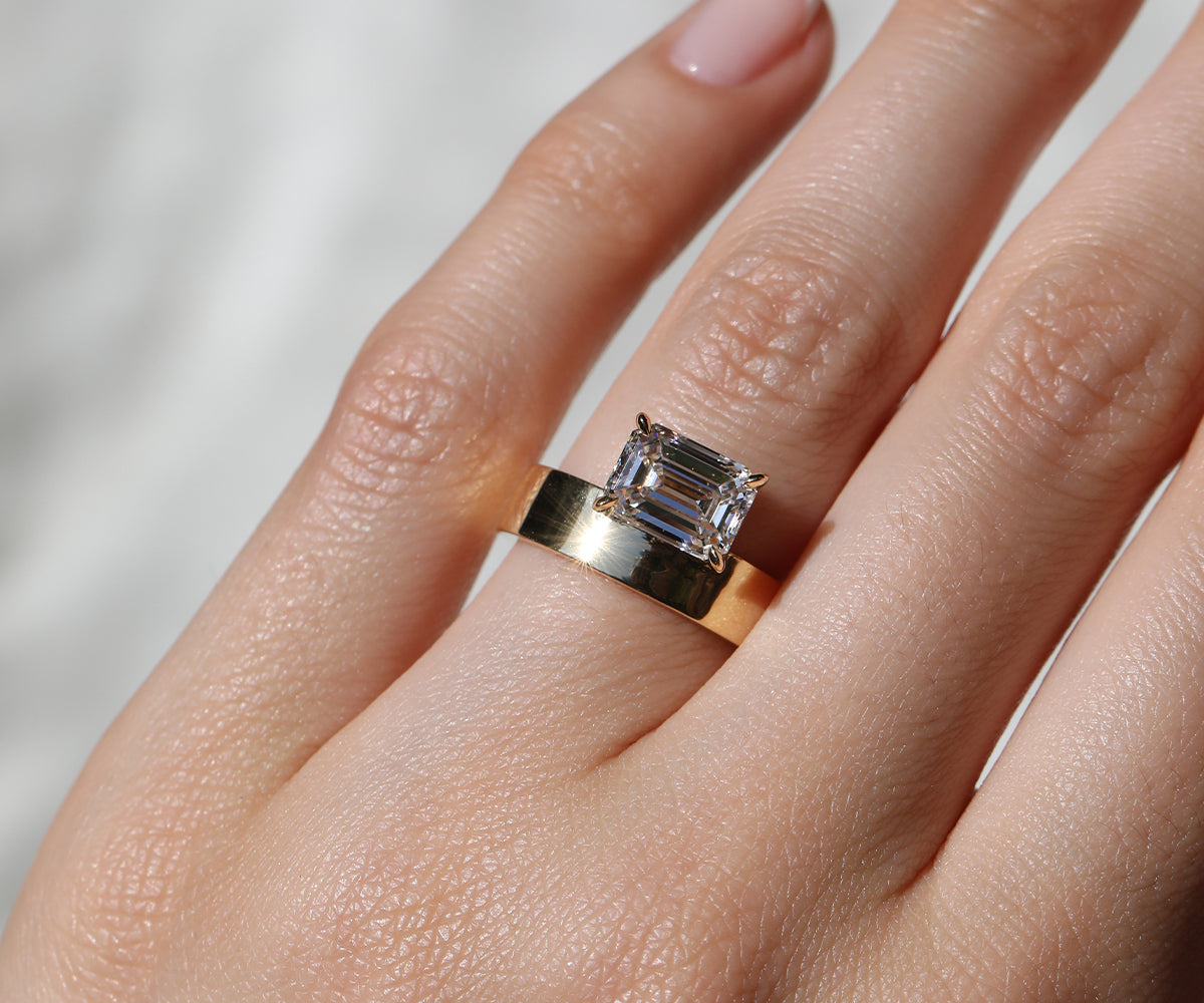 East-west set emerald cut engagement ring with an unusual chunky gold band